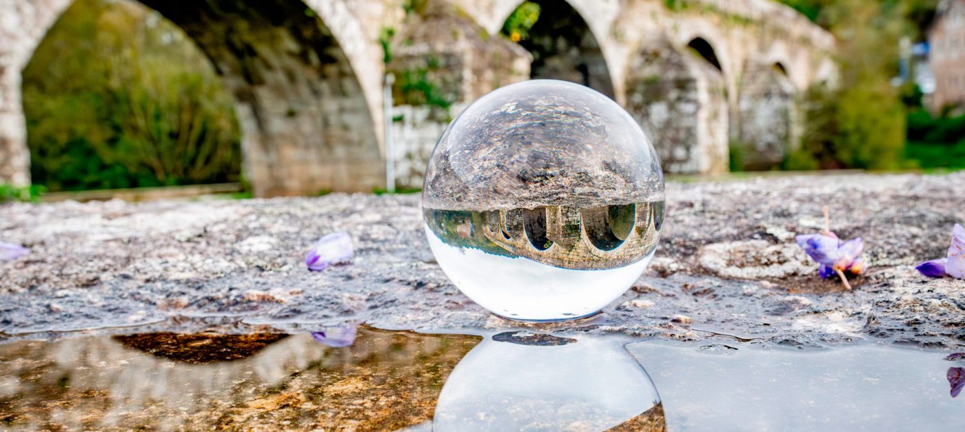 Bóla de cristal sobre a pedra que reflicte, invertida, unha ponte de arcos