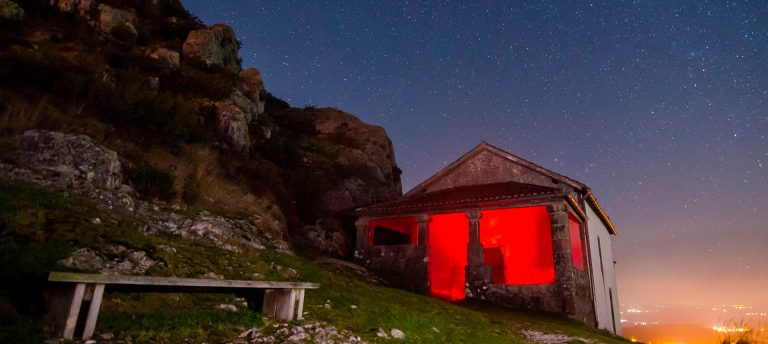 Capela do Pico Sacro iluminada en vermello de noite baixo un ceo estrelado